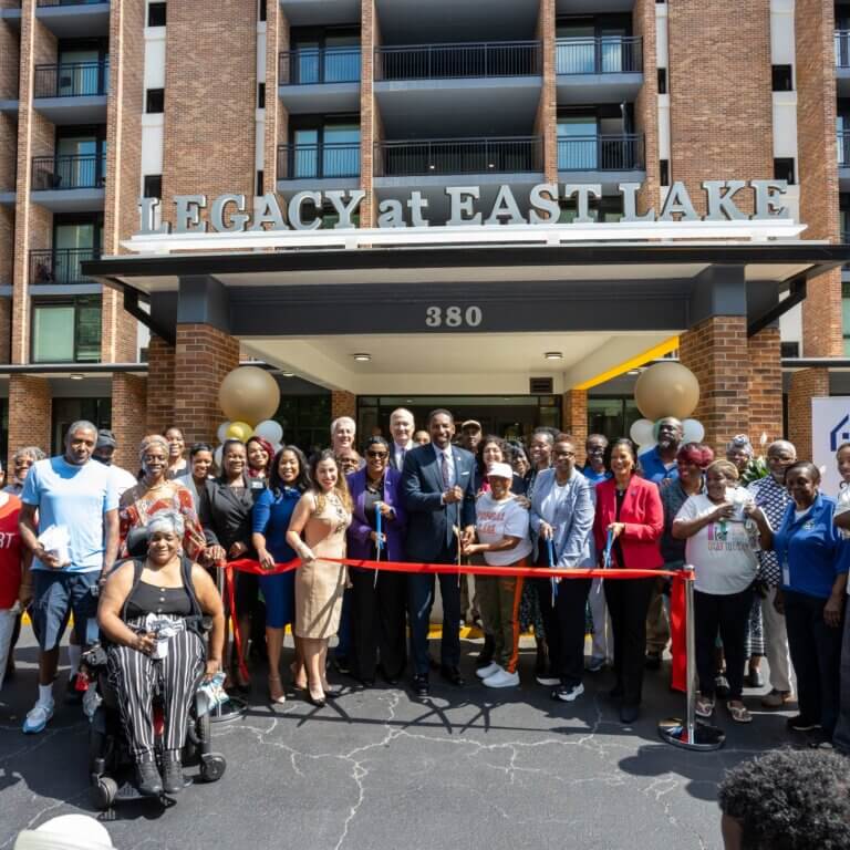 Group of residents, community leaders, and partners gathered in front of Legacy at East Lake for a ribbon-cutting ceremony, celebrating the grand reopening of the newly renovated senior living community in Decatur, Georgia.