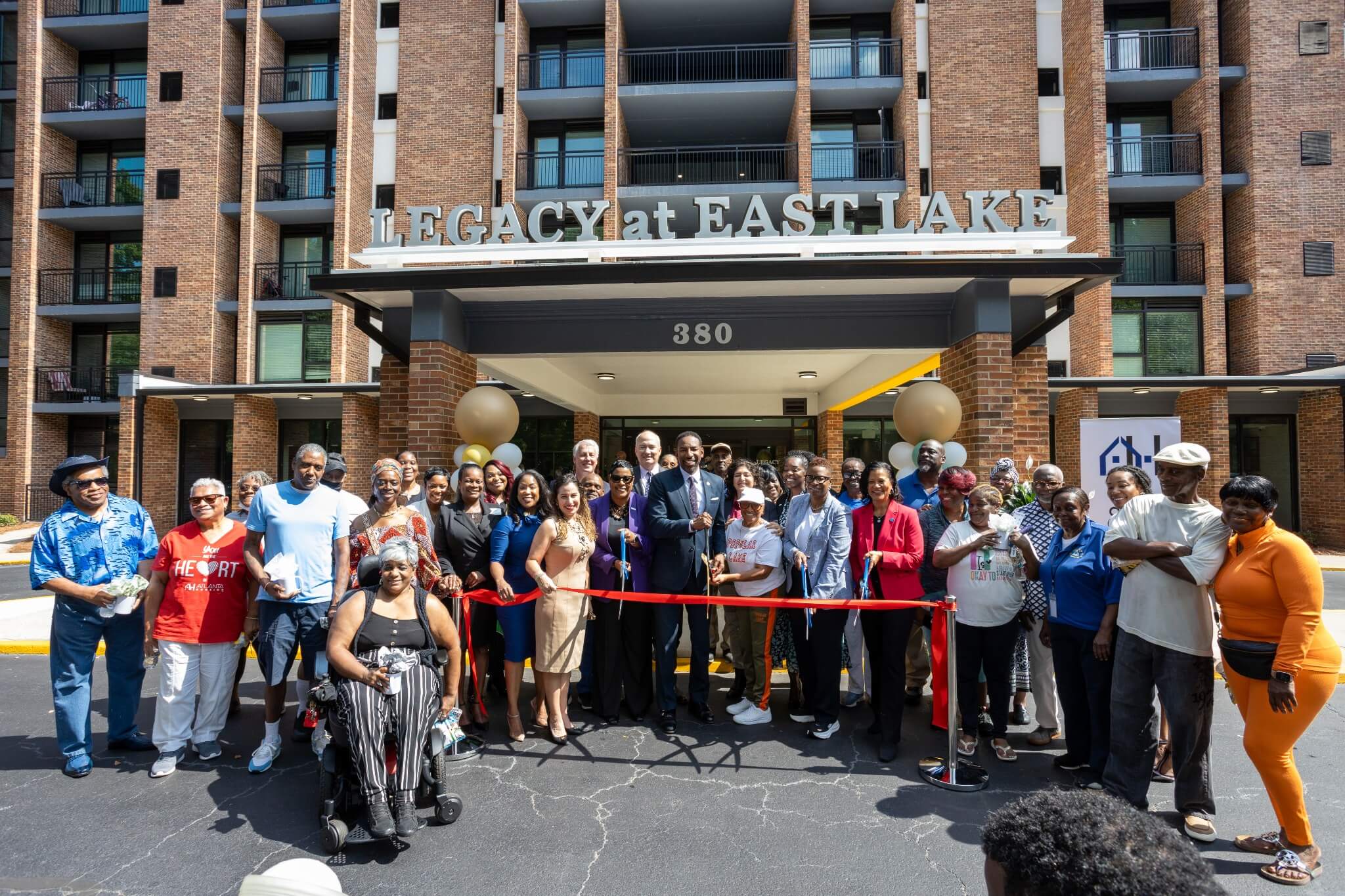 Group of residents, community leaders, and partners gathered in front of Legacy at East Lake for a ribbon-cutting ceremony, celebrating the grand reopening of the newly renovated senior living community in Decatur, Georgia.